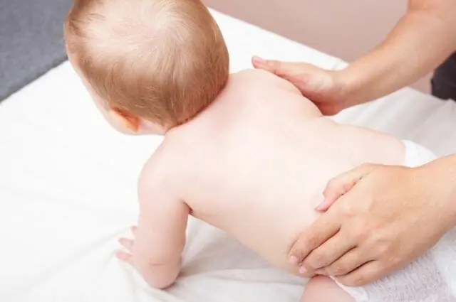 A close-up image of a baby , supported by a chiropractor who is gently adjusting them